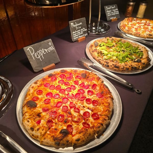 A buffet of three pizzas: pepperoni, mushroom trio, and sweet heat, with ingredient signs.