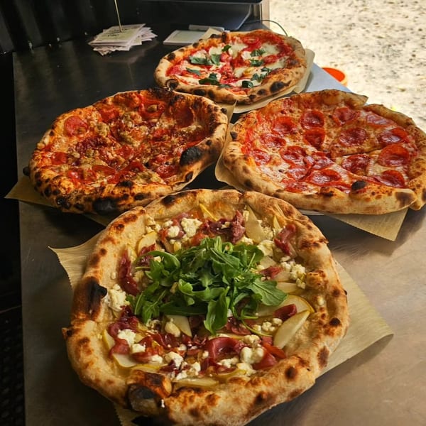 Four delicious pizzas, including pepperoni, sausage, Margherita, and a pear and prosciutto pizza.